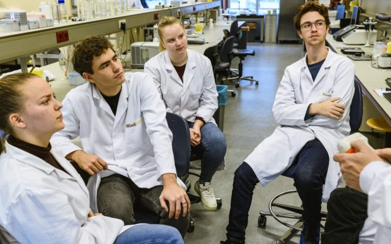 Group of students in a laboratorium listening to a lecturer.