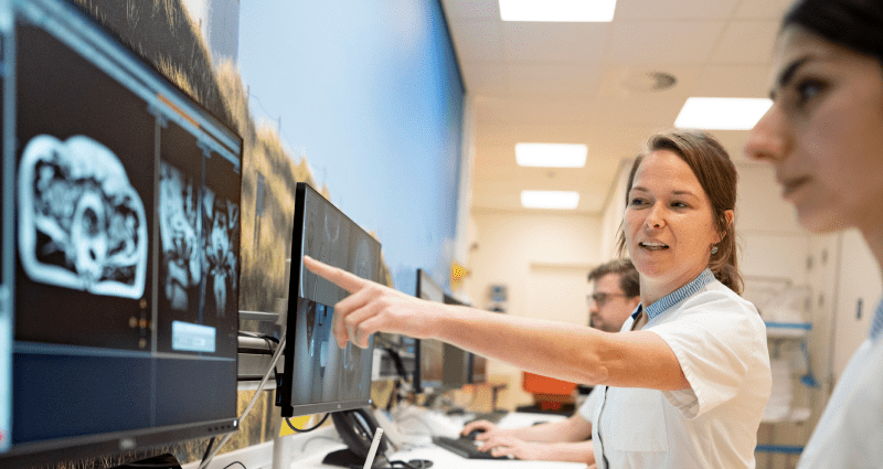 Researcher points to scan on screen while other researcher looks on.