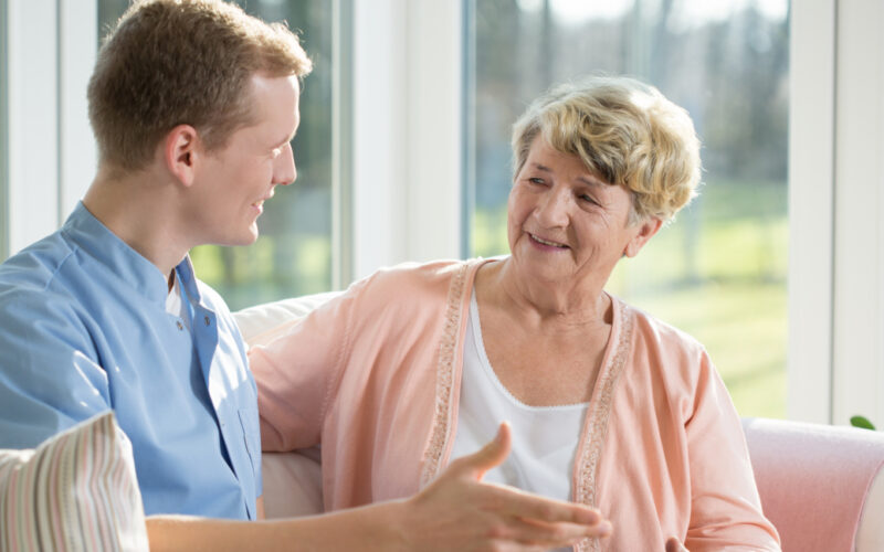Male nurse and senior woman sitting on the couch