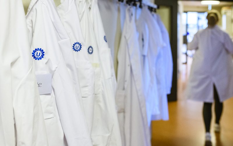 Researcher putting on lab coat and walking to the lab