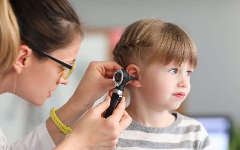 Doctor conducts physical examination of little girl ear.