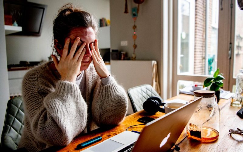 Woman with her hands to her head sitting in front of a laptop