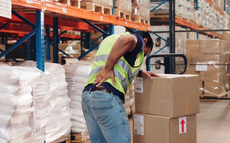 Pallet truck, man and back pain in warehouse with transport.