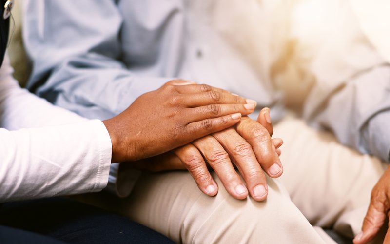 senior person and nurse with holding hands