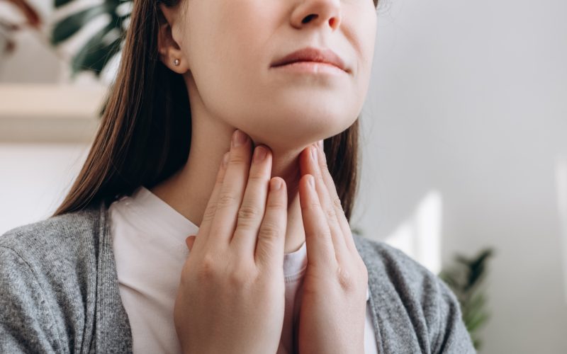 A woman reaches for her throat.