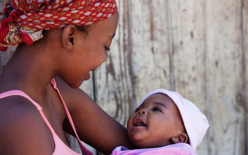 Black woman smiling with a smiling baby in her arms