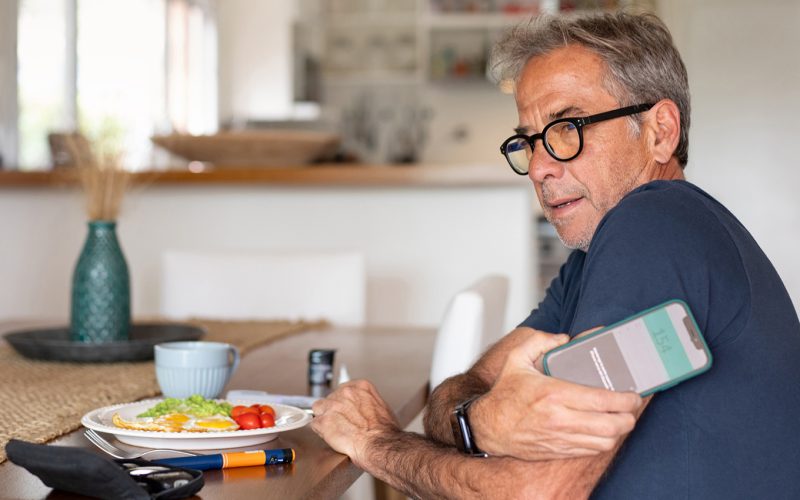 A man at the table measures his blood sugar level with his phone