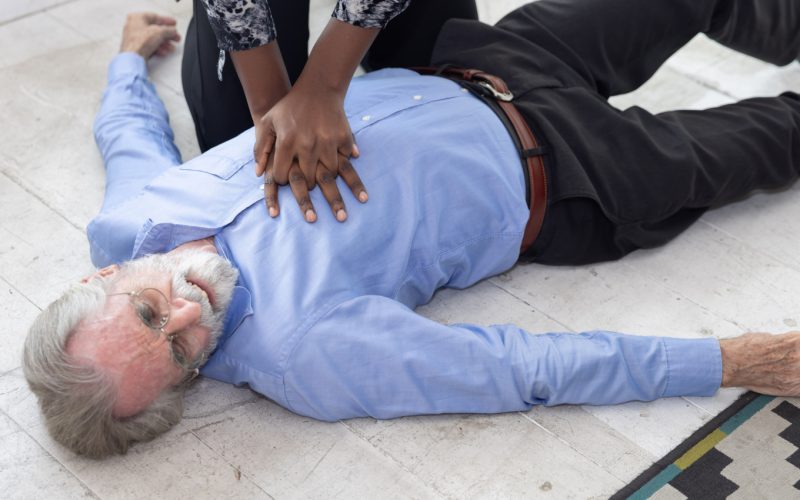 A person tries to revive an older man with a cardiac arrest