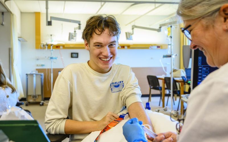 A young man has his blood drawn by a care giver.