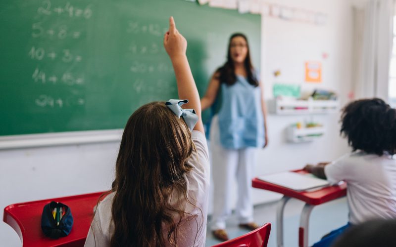 A child raises their hand in a classroom