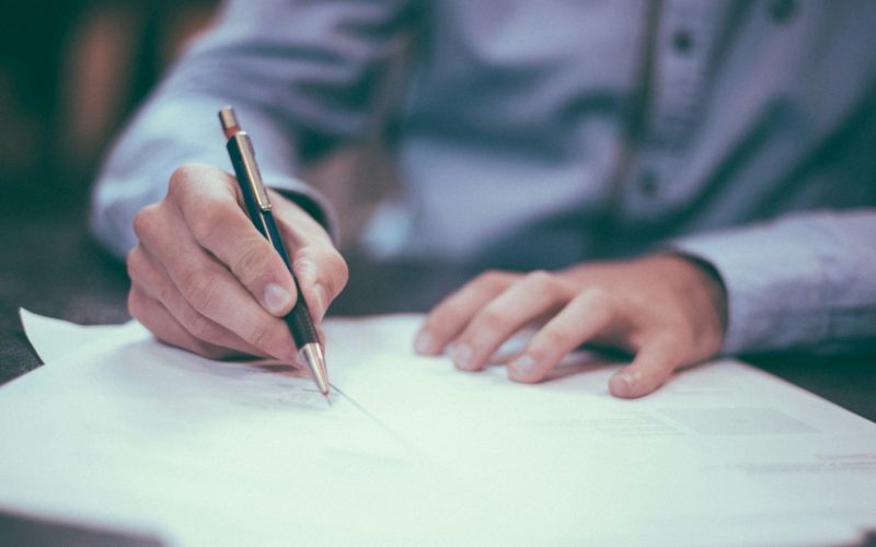 A person signs a set of papers.